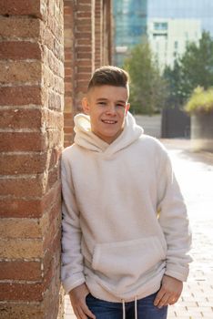 Portrait of young male with hands on pocket leaning on wall outdoors