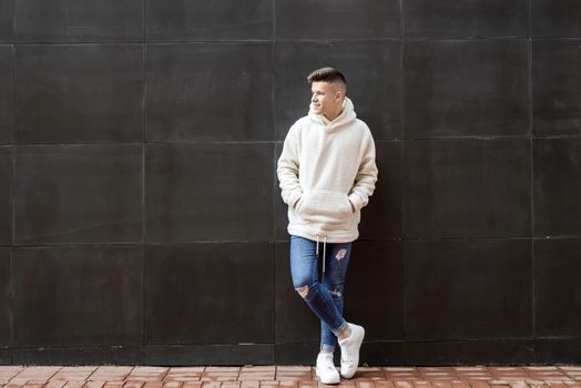 Portrait of young male with hands on pocket leaning on wall outdoors