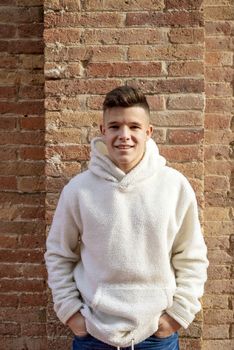 Portrait of young male with hands on pocket leaning on wall outdoors