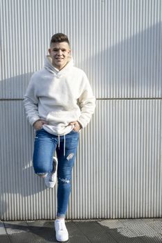 Portrait of young male with hands on pocket leaning on wall outdoors