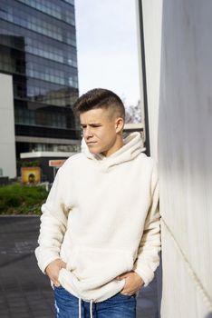 Portrait of young male with hands on pocket leaning on wall outdoors