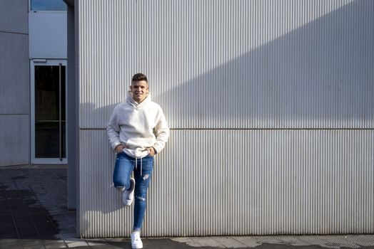 Portrait of young male with hands on pocket leaning on wall outdoors