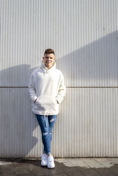 Portrait of young male with hands on pocket leaning on wall outdoors