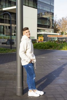 Portrait of young male with hands on pocket leaning on pole outdoors