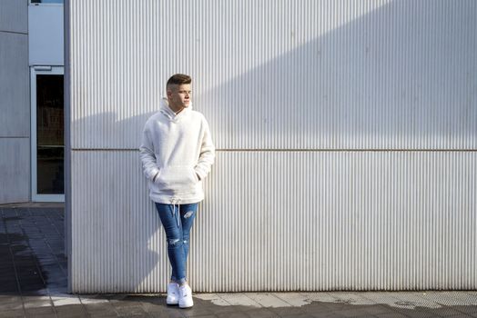 Portrait of young male with hands on pocket leaning on pole outdoors