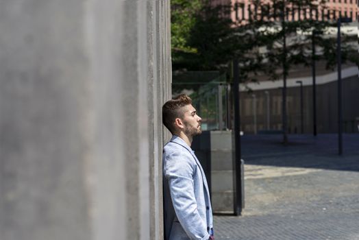 young bearded man leaning against wall and thinking