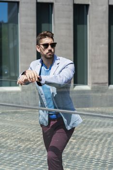 Young bearded man leaning on a fence while looking away in the city