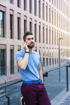 Portrait of cheerful modern businessman speaking by phone and smiling while standing outdoors