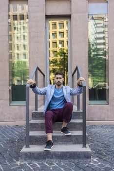 Portrait of happy bearded young man sitting on steps