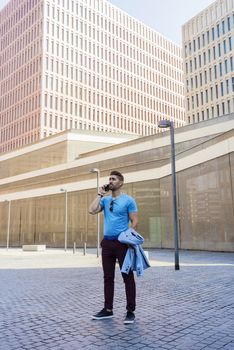 Portrait of cheerful modern businessman speaking by phone and smiling while standing outdoors