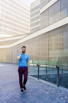 Portrait of cheerful modern businessman speaking by phone and smiling while standing outdoors