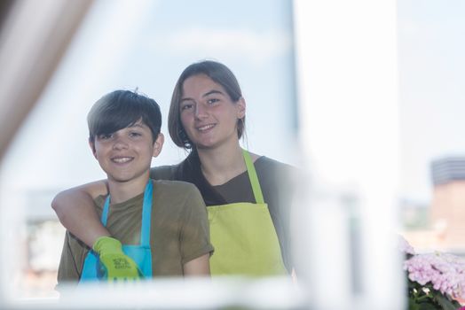 Two teenager wearing gardener apron posing at home terrace