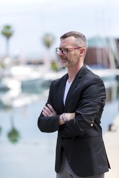 Businessman standing in the city arms crossed while looking away and smiling