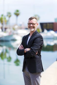 Businessman standing in the city arms crossed while looking camera and smiling