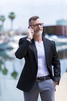 Businessman at loading dock wearing formal clothes, using smartphone