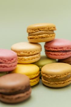 Vintage pastel colored French macaroons or macarons on green background