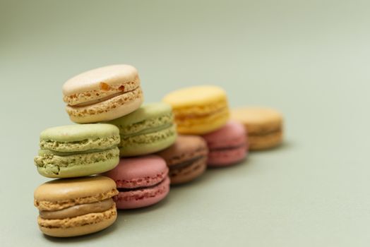 Vintage pastel colored French macaroons or macarons on green background