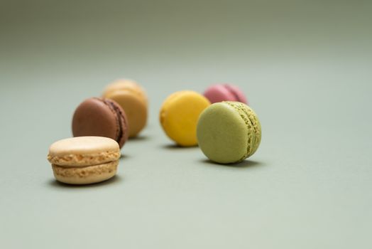 Vintage pastel colored French macaroons or macarons on green background