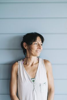 Hispanic woman with summer dress and ponytail while leaning on wood wall