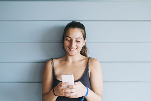 Beautiful woman leaning on a wood wall while using a smartphone