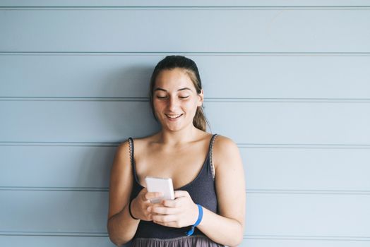 Beautiful woman leaning on a wood wall while using a smartphone