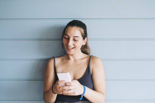 Beautiful woman leaning on a wood wall while using a smartphone