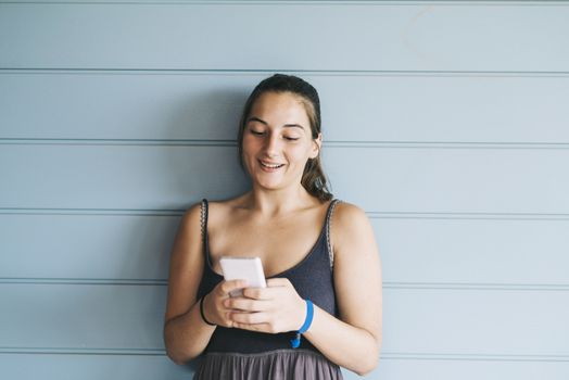 Beautiful woman leaning on a wood wall while using a smartphone