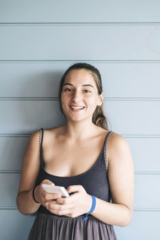 Beautiful woman leaning on a wood wall while using a smartphone