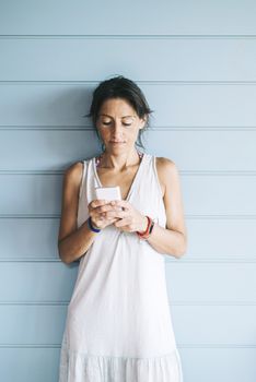 Beautiful woman leaning on a wood wall while using a smartphone