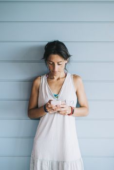 Beautiful woman leaning on a wood wall while using a smartphone