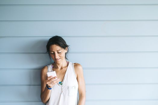 Beautiful woman leaning on a wood wall while using a smartphone