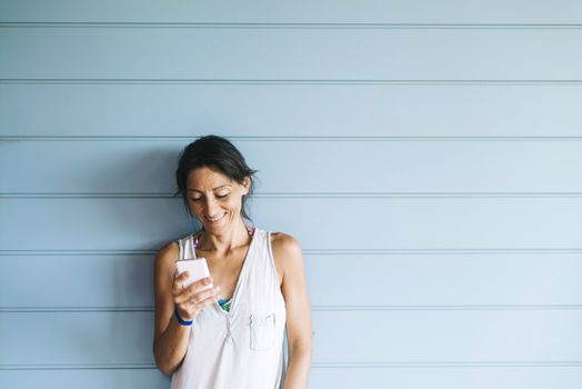 Beautiful woman leaning on a wood wall while using a smartphone