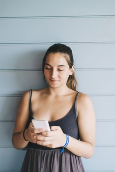 Beautiful woman leaning on a wood wall while using a smartphone