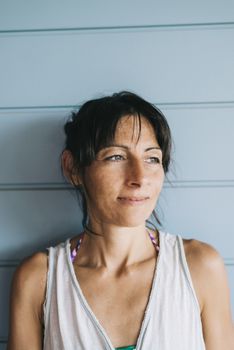 Hispanic woman with summer dress and ponytail while leaning on wood wall