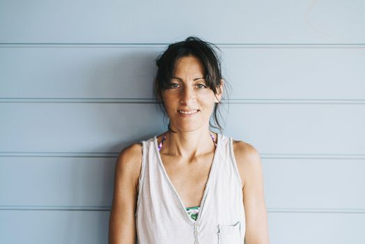 Hispanic woman with summer dress and ponytail while leaning on wood wall