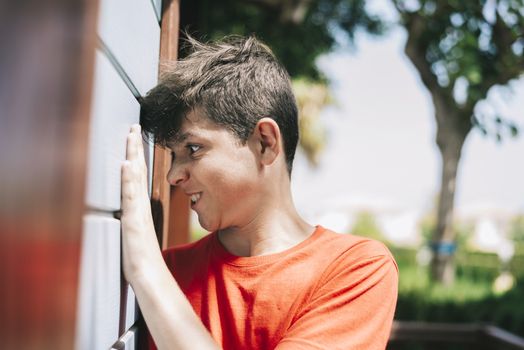 Side view of teenage male grimacing against a outdoors wall