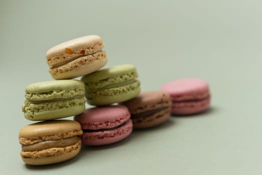 Colored tasty  macaroons over a green background.