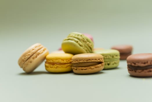 Colored tasty  macaroons over a green background.