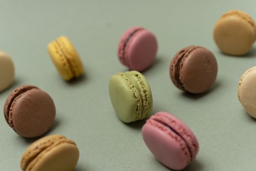 Colored tasty  macaroons over a green background.
