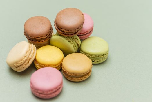 Colored tasty  macaroons over a green background.