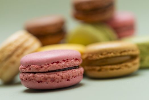 Colored tasty  macaroons over a green background.