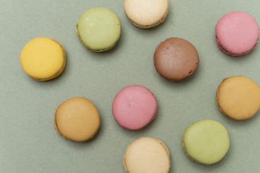 Colored tasty  macaroons over a green background.