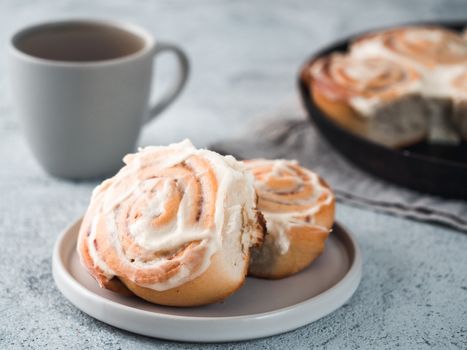 Vegan swedish cinnamon buns Kanelbullar with pumpkin spice,topping vegan cream cheese in plate with tea cup on table. Idea and recipe pastries - perfect cinnamon rolls. Copy space. Shallow DOF