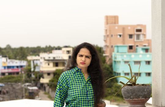 A beautiful Indian woman and wearing a green shirt and the back of Chennai City blur background