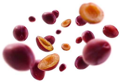 Red plums levitate on a white background.