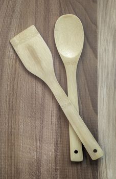 On a wooden table, kitchen utensils: a wooden spatula and a spoon. The view from the top, flat position, copy space