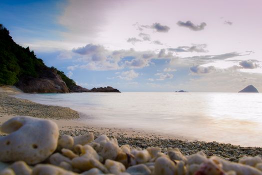 Peaceful and tropical coral turtle beach at Perhentian Islands, Malaysia, long exposure, with cloudy sky during sunset.. Postcard, mural or wallpaper about Malaysian tourism or travel