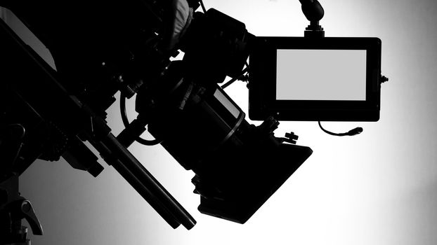 Silhouette images of video camera in tv commercial studio production which operating or shooting by cameraman and film crew team in set and prop on professional crane and tripod for easy to pan tilt or shift