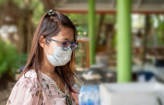 A woman wearing a mask and glasses is standing to shop.