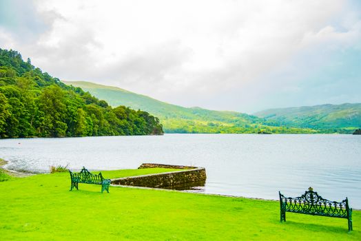 Empty benches on the shore of lake ullswater with beautiful view of the lake